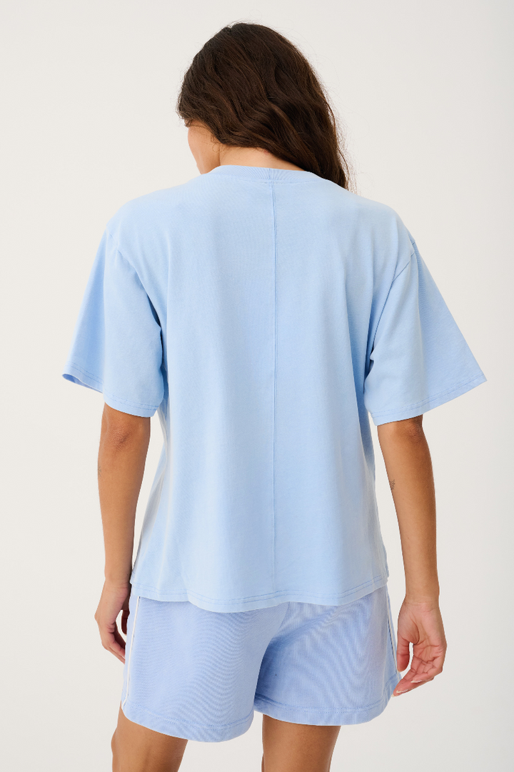 Person wearing a light blue outfit with a t-shirt and shorts on a plain background