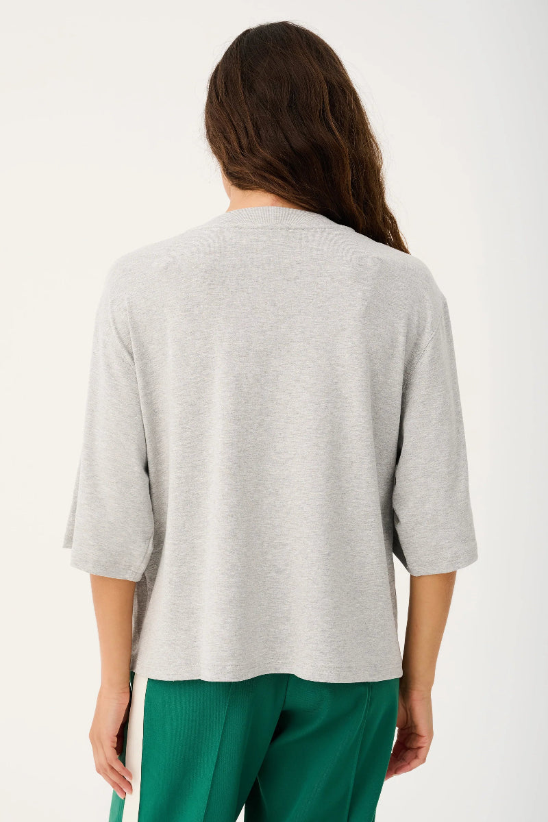 Person wearing a gray sweater and green pants on a white background