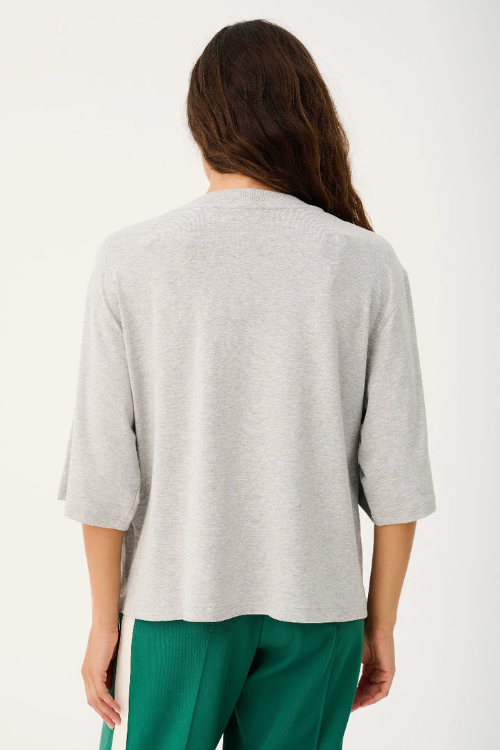 Person wearing a gray sweater and green pants on a white background