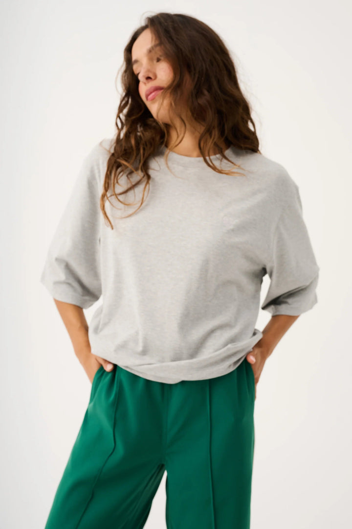 Woman wearing a gray sweater and green pants on a white background