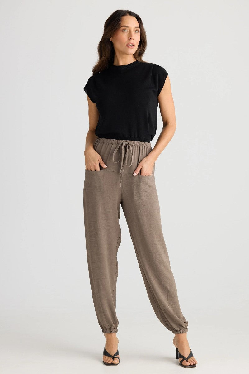 Woman wearing a black top and brown pants on a white background