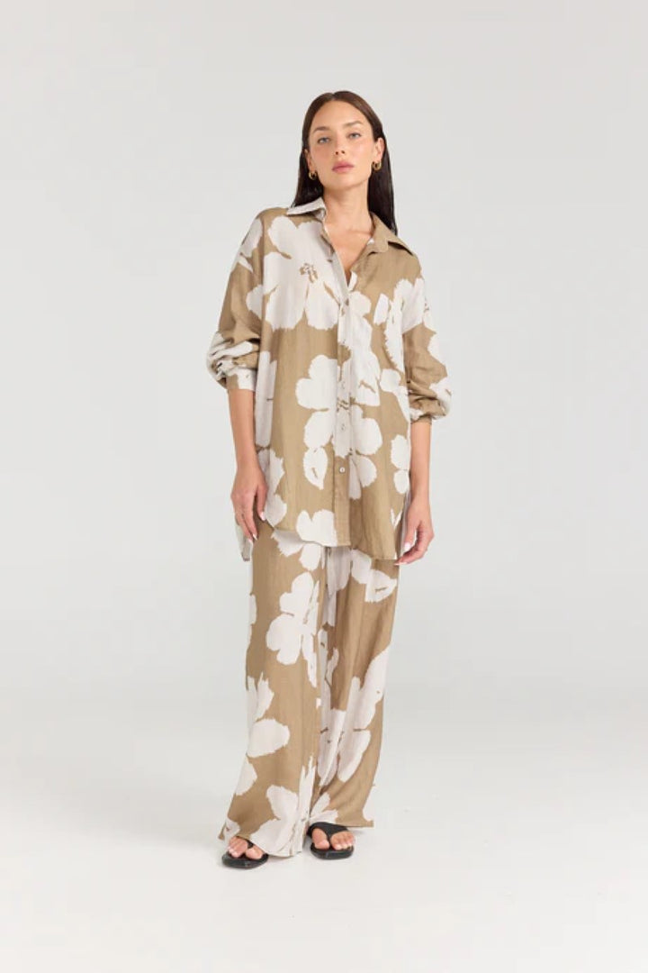Woman wearing a beige and white floral outfit on a white background