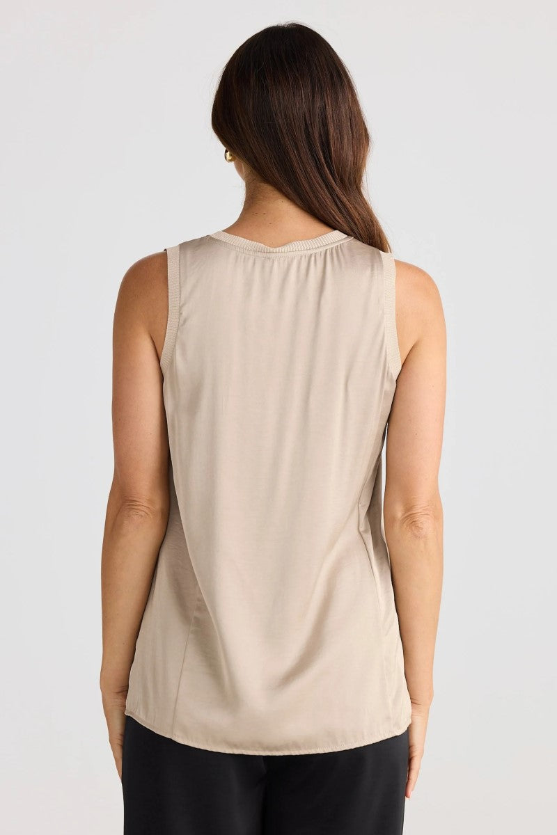 Woman wearing a beige sleeveless top on a white background