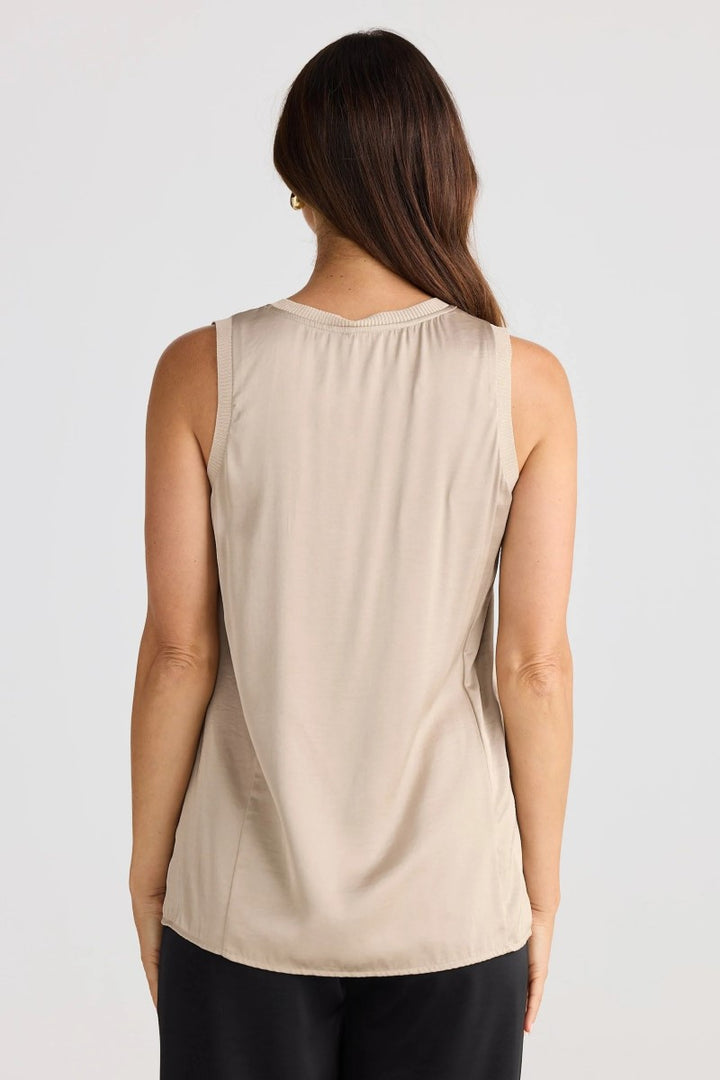 Woman wearing a beige sleeveless top on a white background