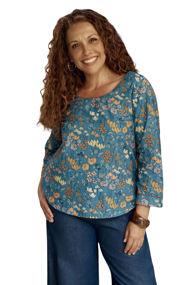 Woman wearing a blue floral blouse and jeans on a white background