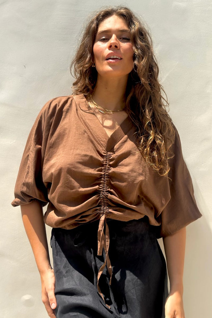 Woman wearing a brown top with a plain background