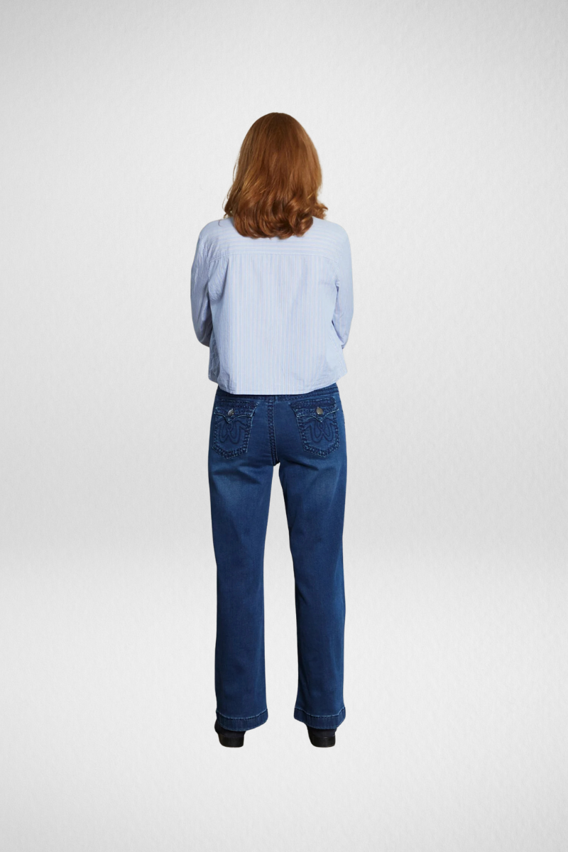 Woman wearing a blue shirt and blue jeans on a white background back view