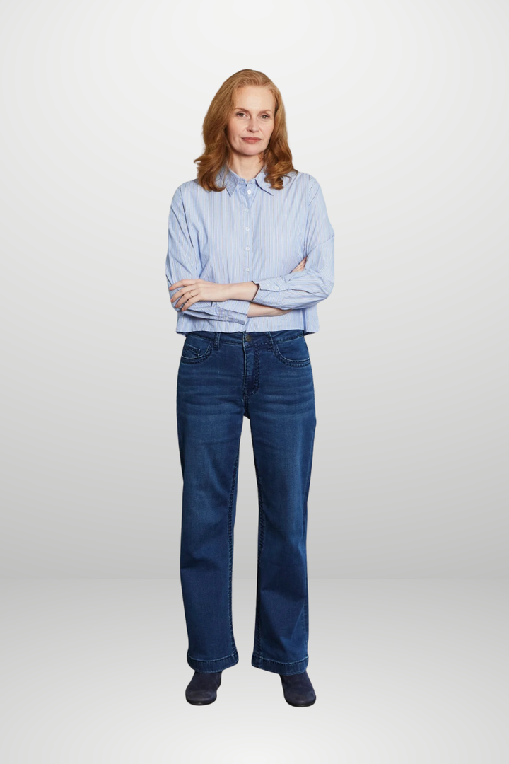 Woman wearing a blue shirt and blue jeans on a white background