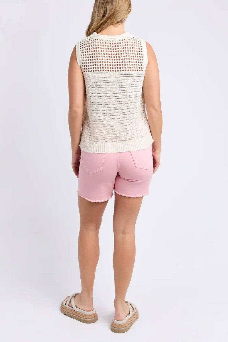 Person wearing a sleeveless patterned top and pink shorts on a white background