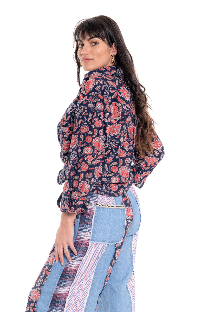 Woman wearing a floral blouse and denim pants on a white background