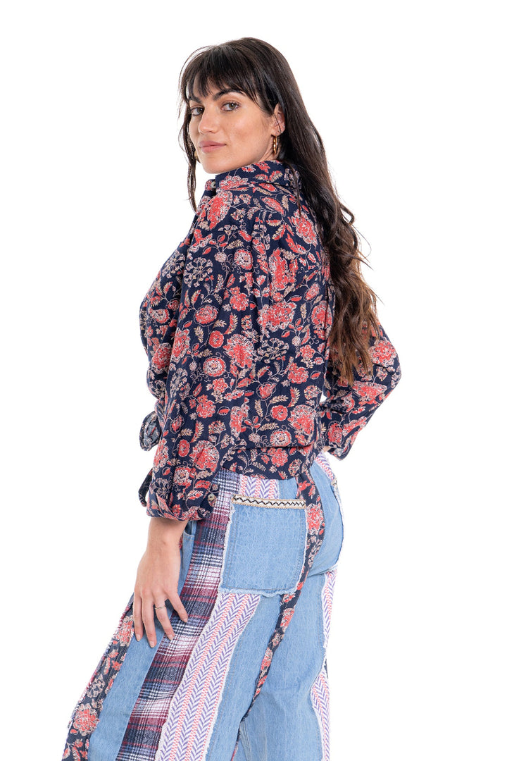 Woman wearing a floral blouse and denim pants on a white background