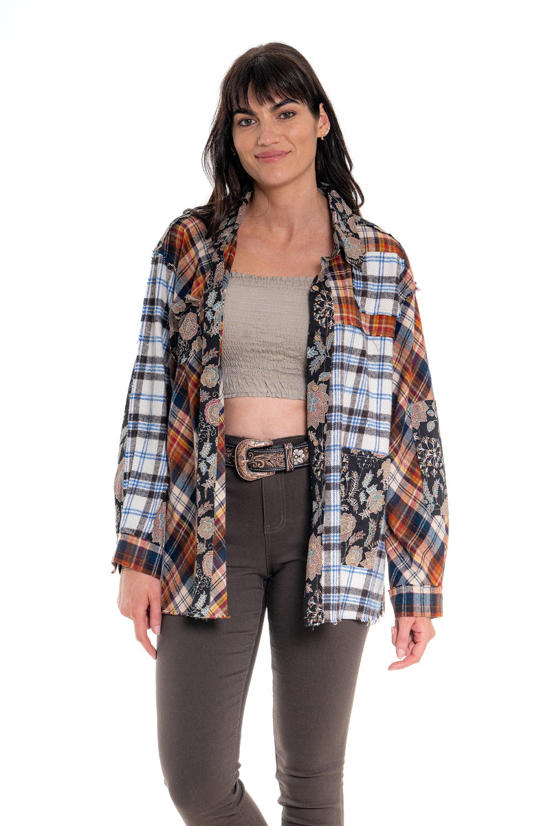 Woman wearing a plaid shirt over a tank top with brown pants on a white background