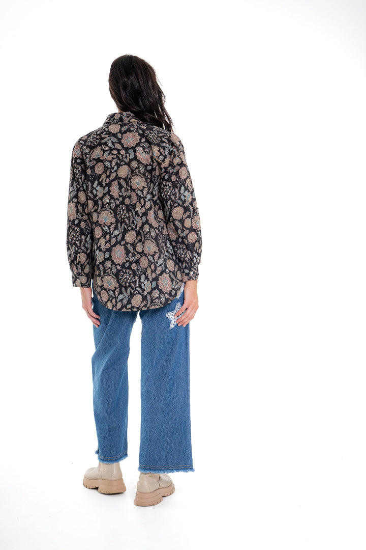 Person wearing a patterned shirt and blue jeans on a white background