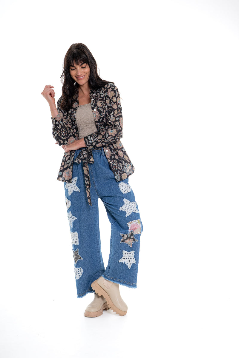 Woman wearing a floral jacket and blue jeans with star patterns on a white background