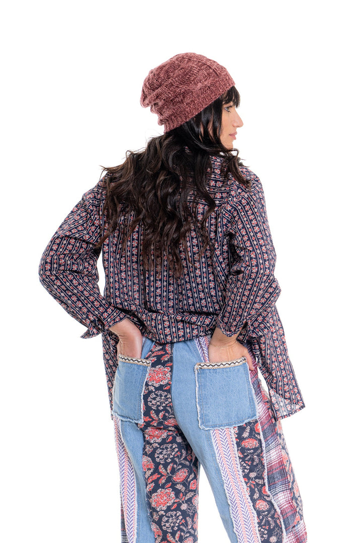 Woman wearing a patterned jacket, blue top, and light blue jeans on a white background
