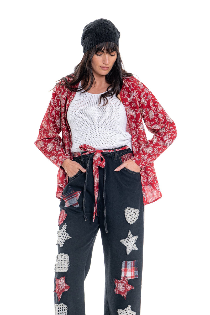 Woman wearing a red floral shirt and black pants with star patterns on a white background