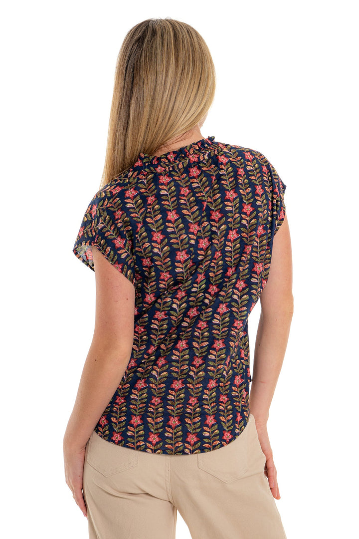 Back view of navy floral blouse with beige pants.