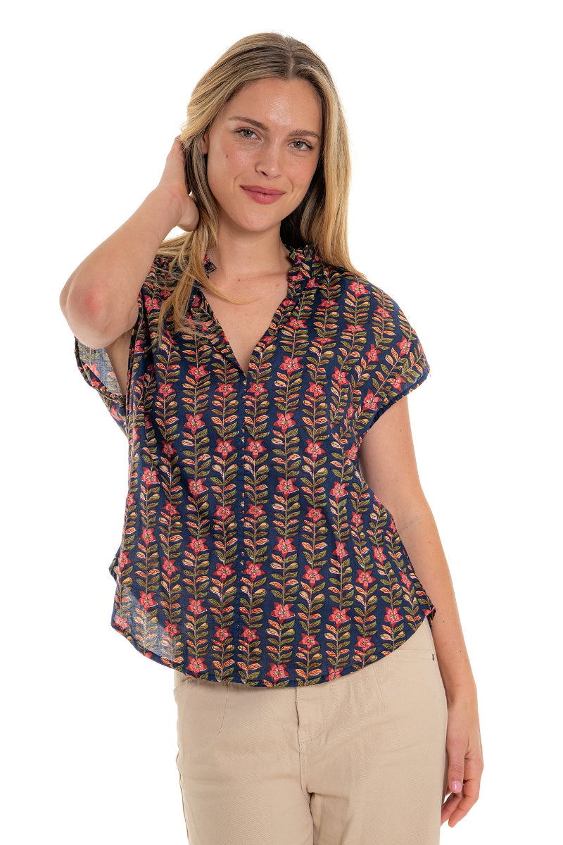 Front view of woman in navy floral blouse and beige pants.