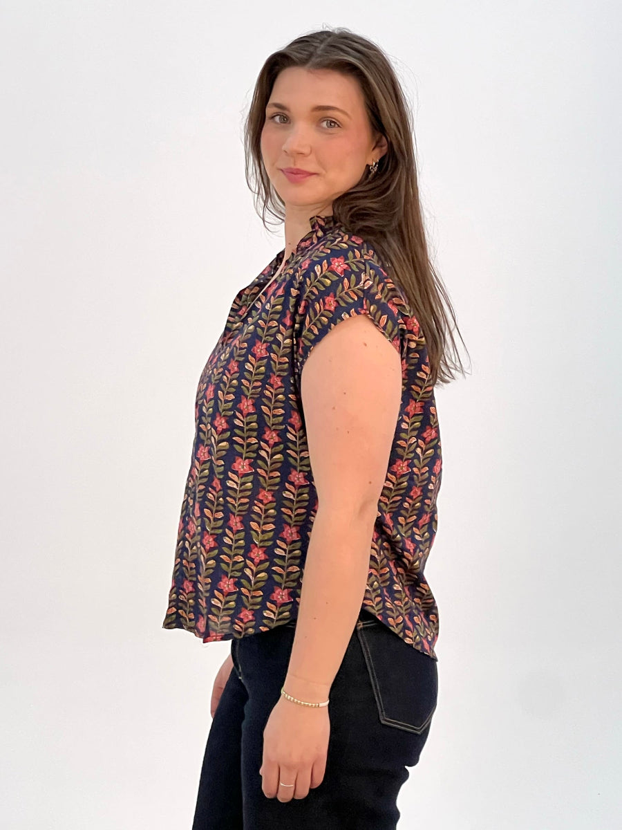Side view of woman wearing navy floral blouse and dark jeans.