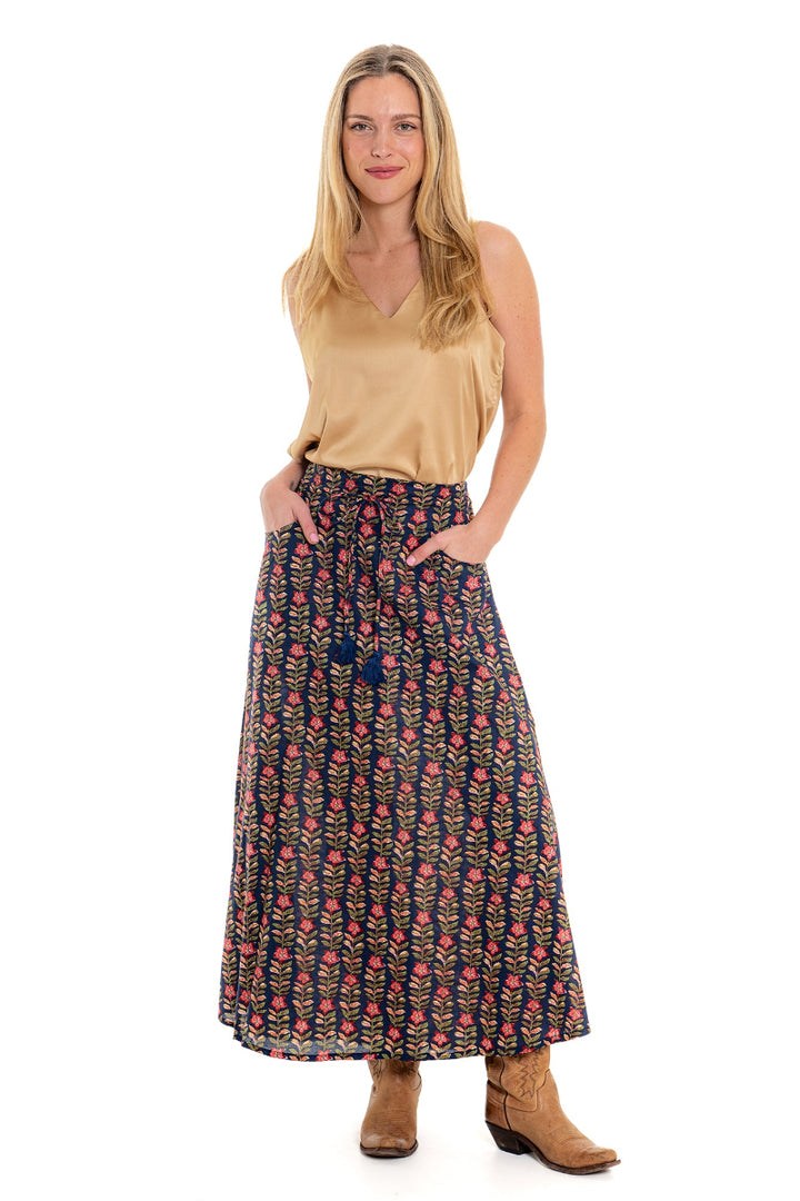 Front view of woman wearing beige top and patterned maxi skirt with boots.