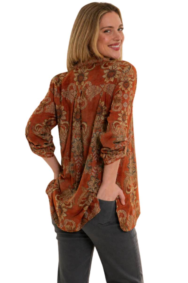 Woman wearing a patterned orange blouse on a white background