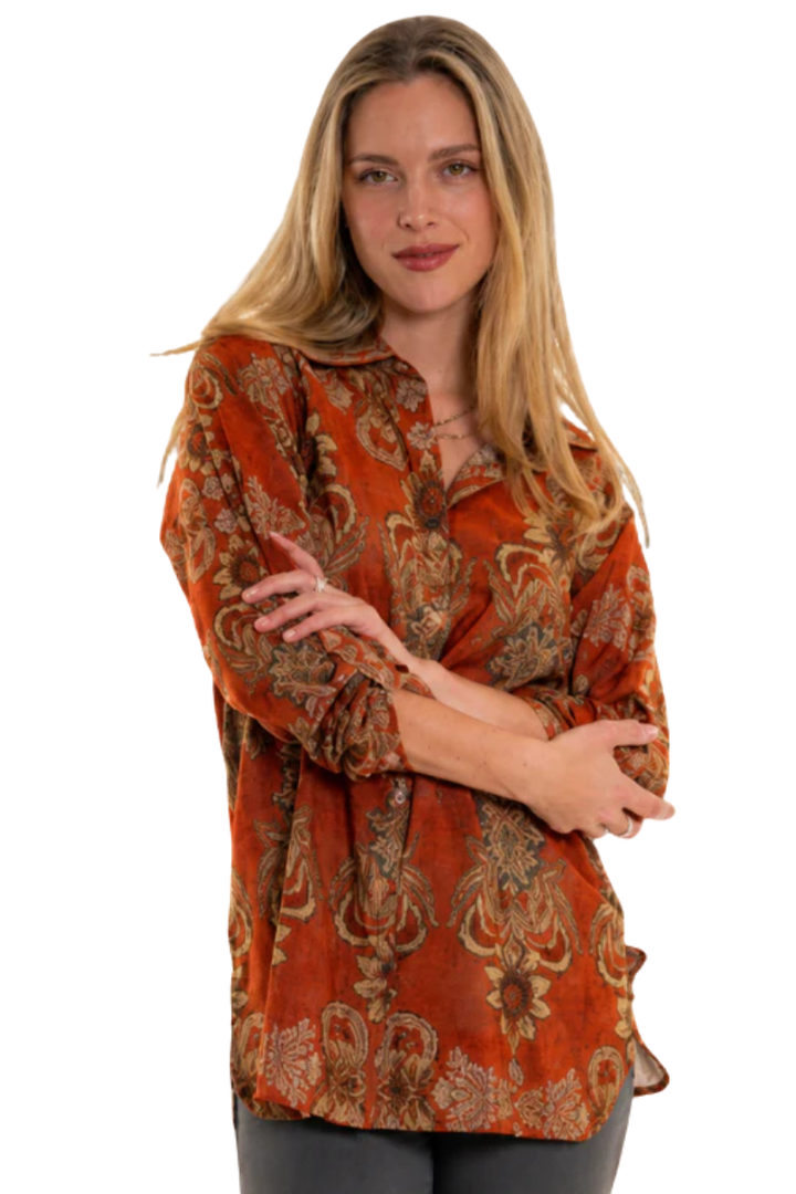 Woman wearing a patterned orange blouse on a white background