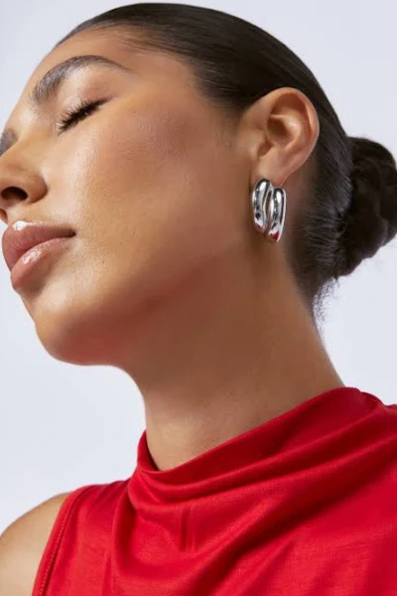 The Claire Earrings in Silver by Zahar are shown worn on the model, highlighting their elegant twisted double band design and contemporary shine — available at Ivy Vibe.
