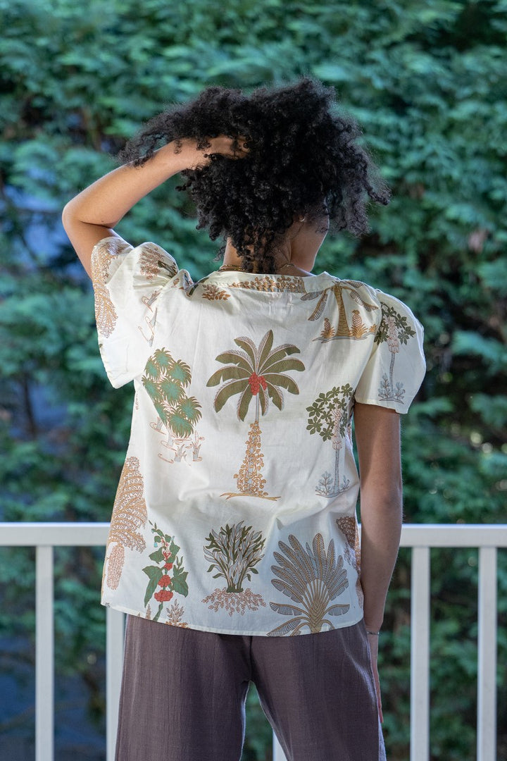 Person wearing a patterned shirt with palm tree design outdoors