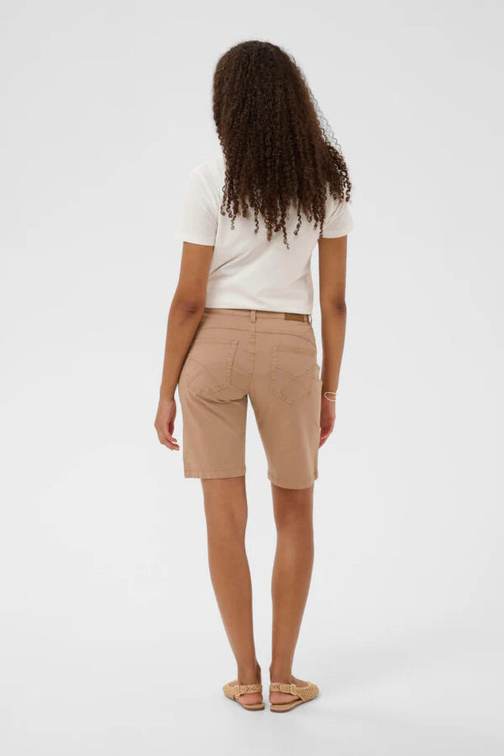 Person wearing beige shorts and a white top on a white background