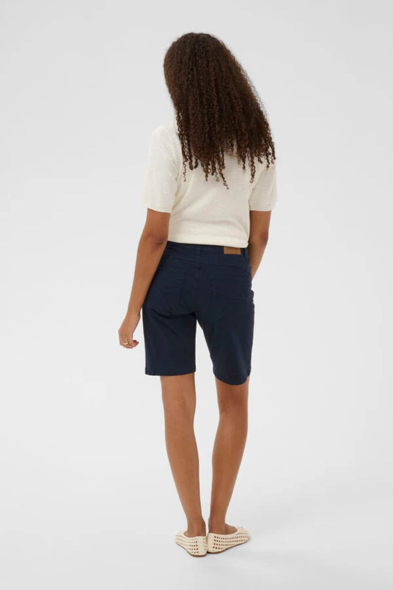 Person wearing a white shirt and navy shorts on a light gray background