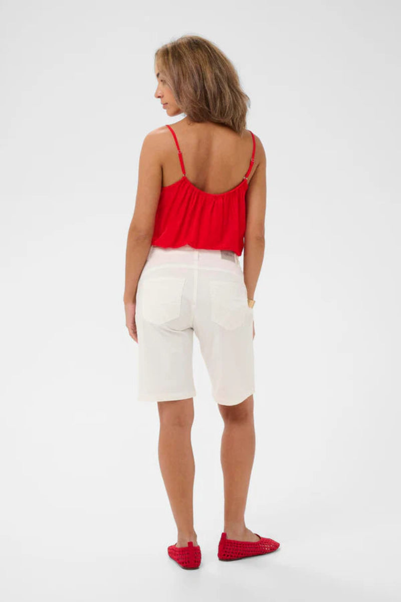 Woman wearing a red top and white shorts on a white background