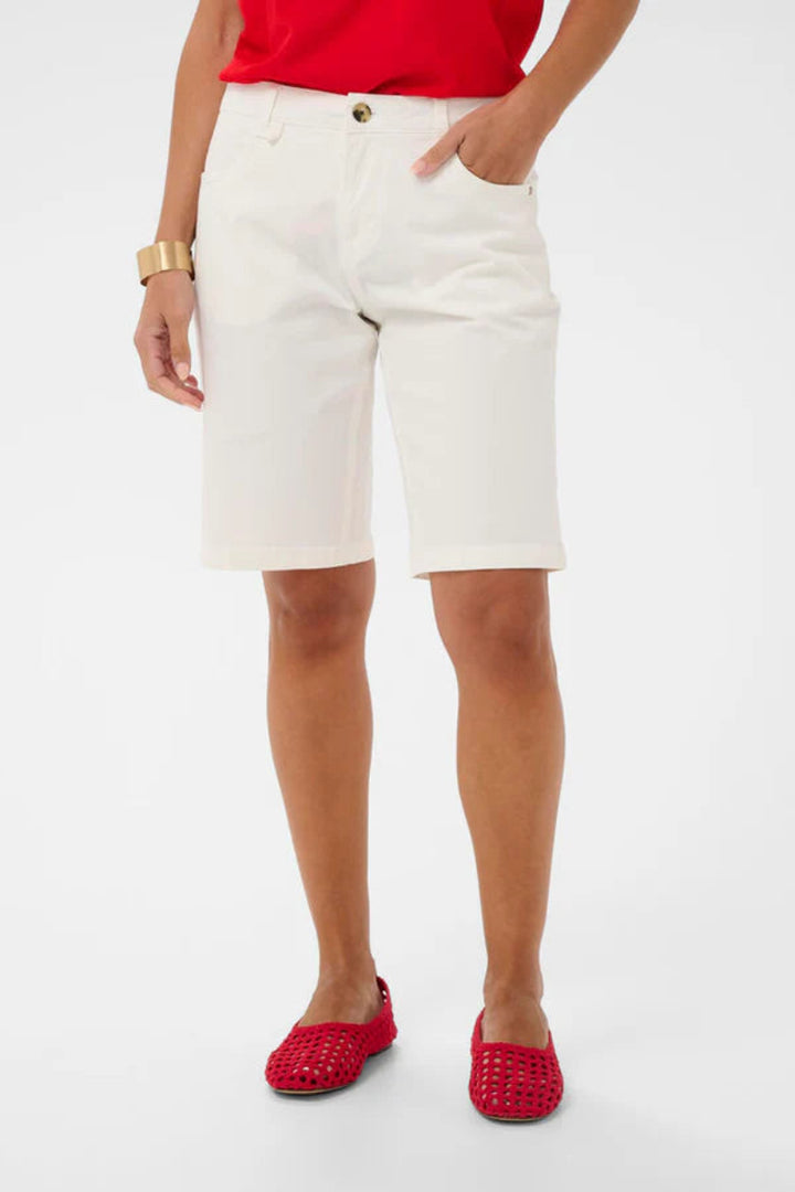 A model wearing white denim shorts, a red top, and red woven flat shoes, shown from the waist down against a plain white studio background.