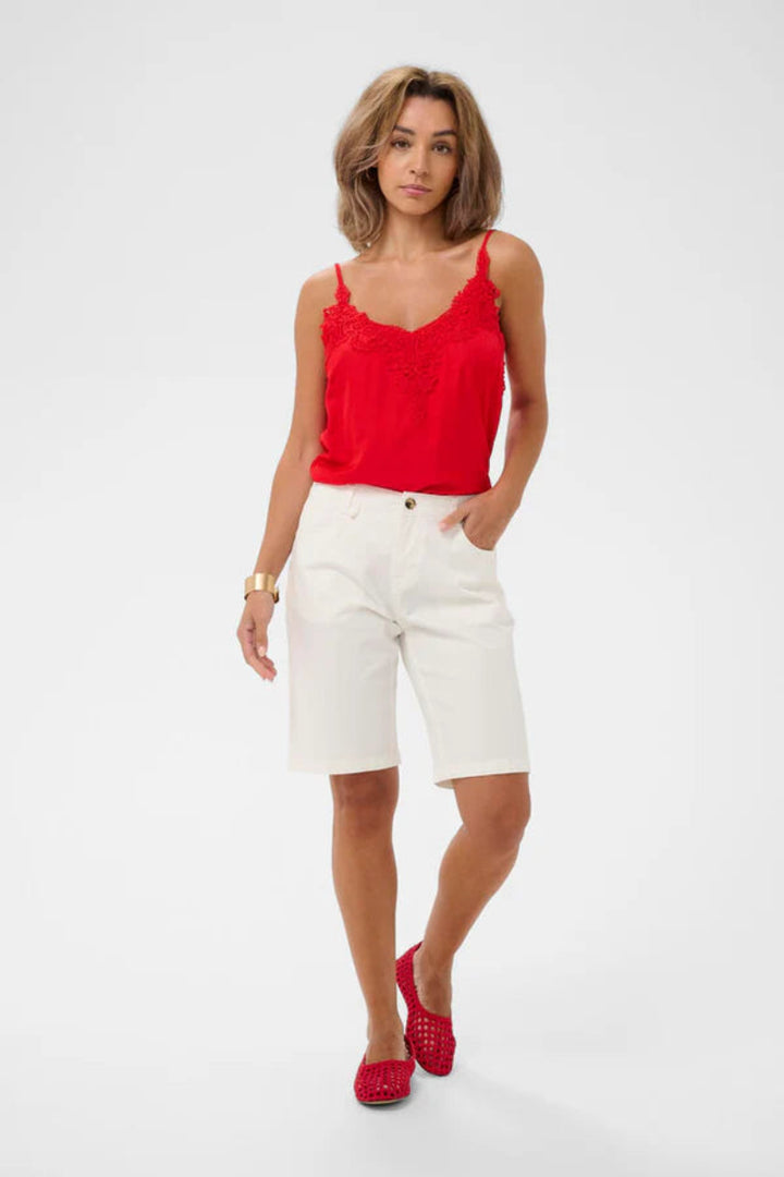 Woman wearing a red top and white shorts on a white background