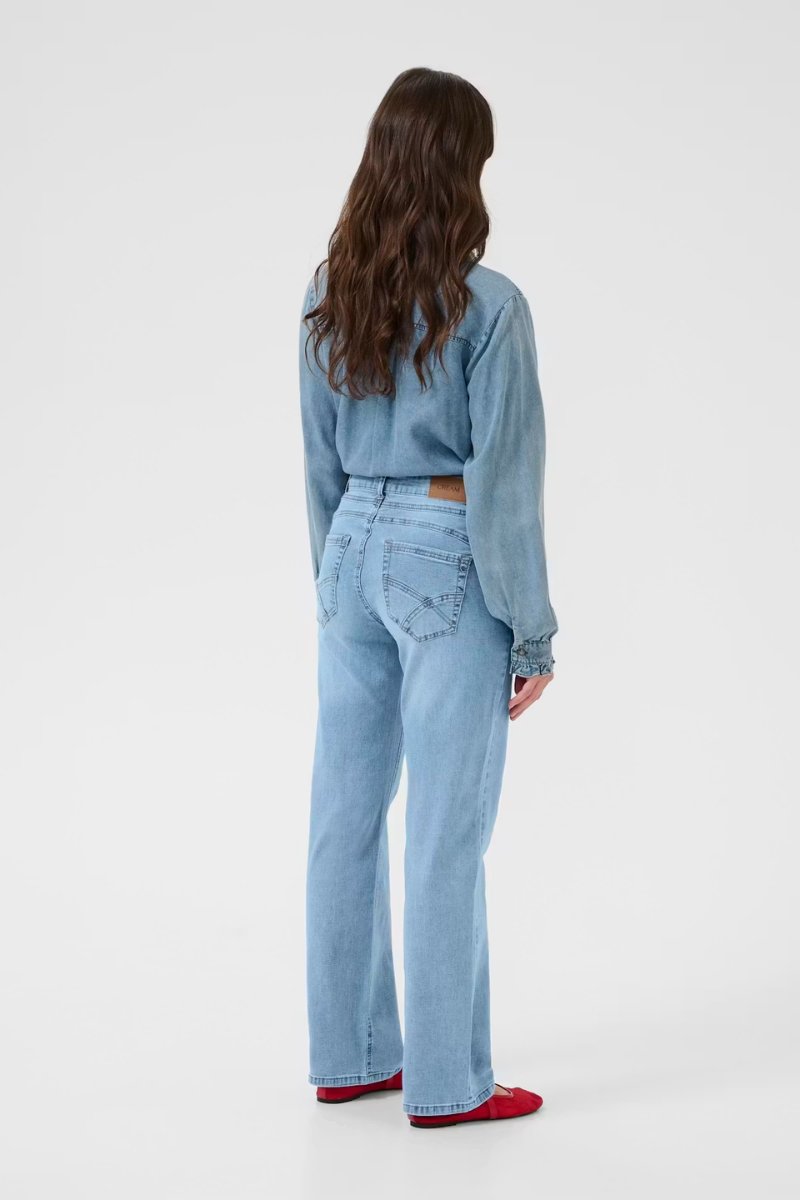 Person wearing a light blue denim outfit on a white background