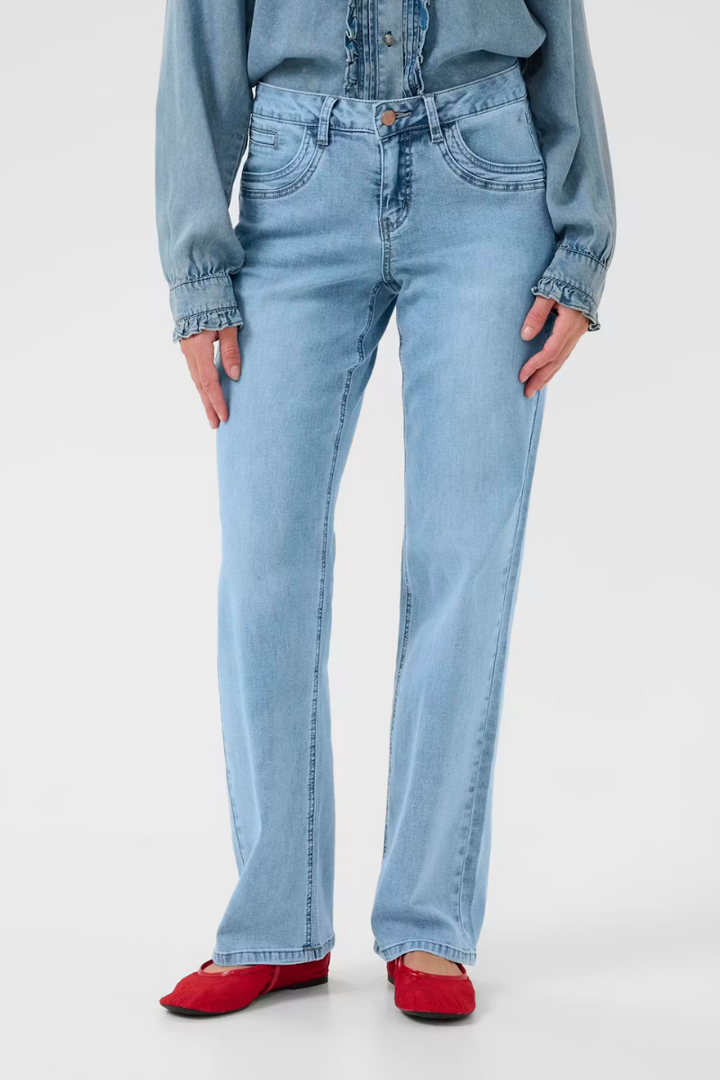 Person wearing light blue jeans and a matching denim shirt on a white background