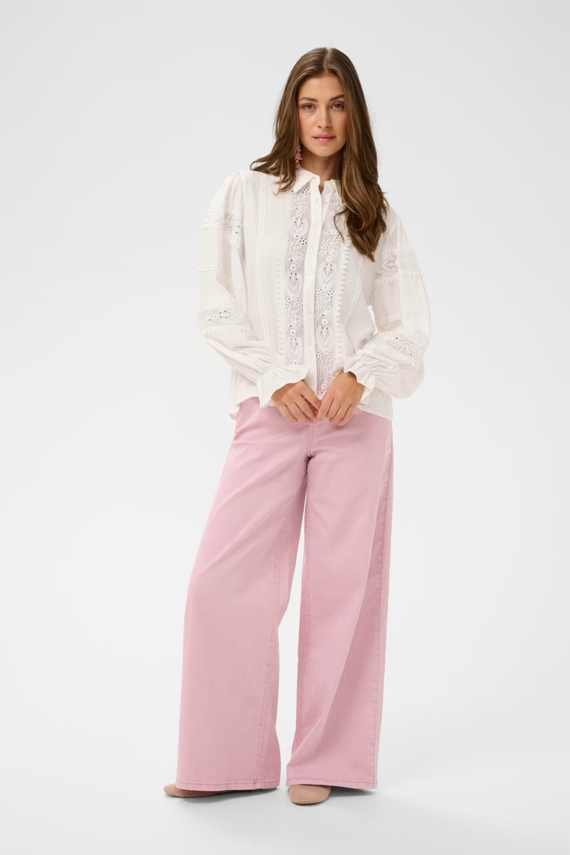 Woman wearing a white blouse and pink pants on a white background