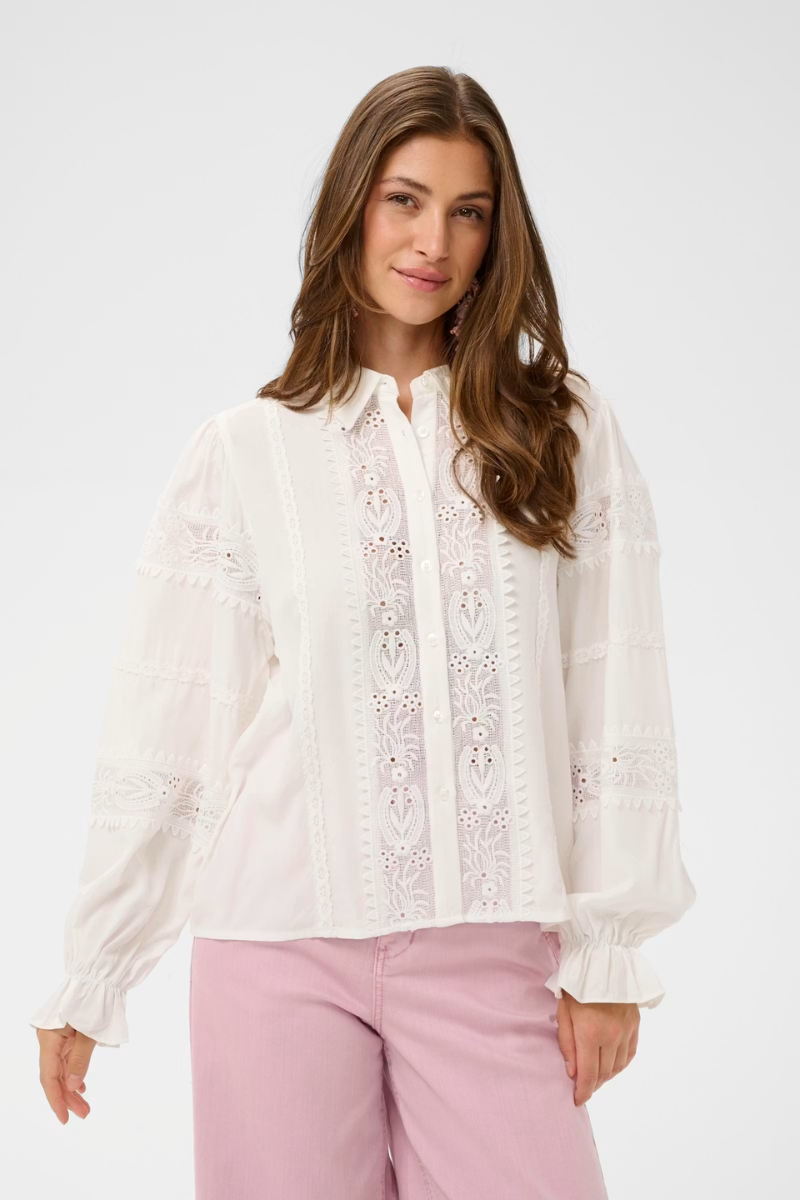 Woman wearing a white blouse with lace details on a white background
