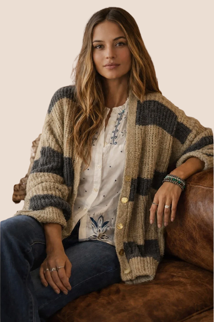 Woman wearing a patterned cardigan sitting on a leather couch.