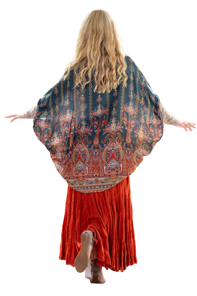 Person wearing a patterned shawl over an orange dress on a white background