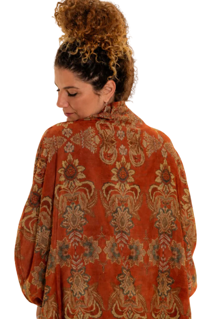Woman wearing a patterned orange garment on a white background