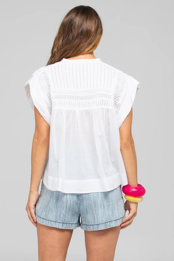 Woman wearing a white sleeveless top and denim shorts on a gray background