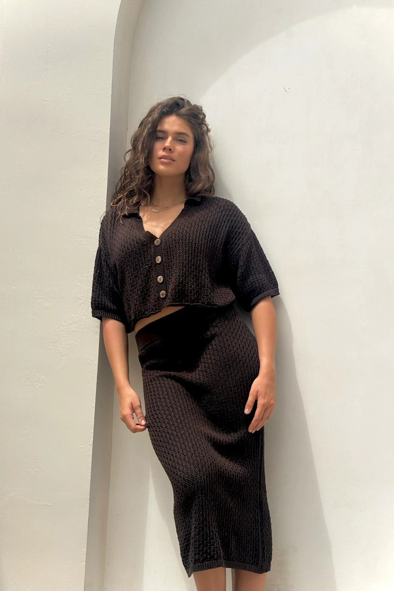 Woman wearing a black textured outfit against a plain background