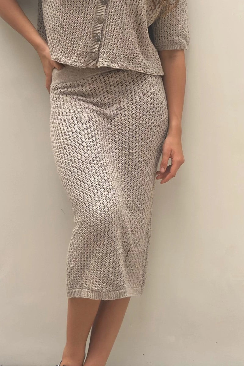 Person wearing a matching textured knit top and skirt against a plain background