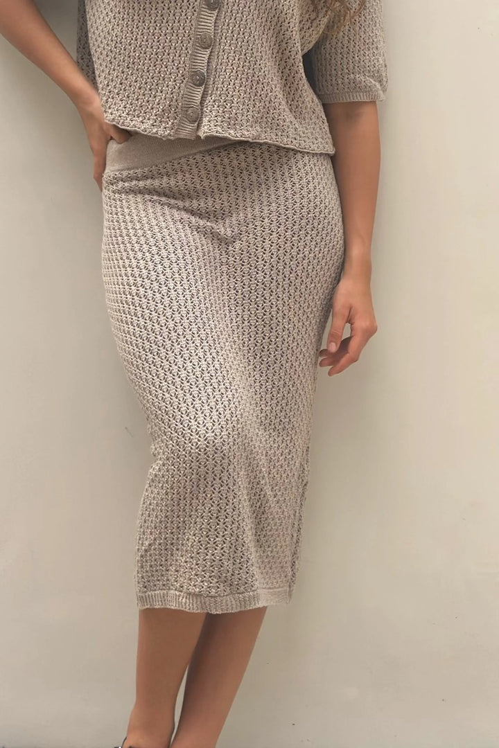 Person wearing a matching textured knit top and skirt against a plain background