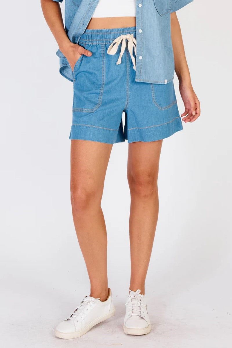 Person wearing blue denim shorts and a matching jacket on a white background