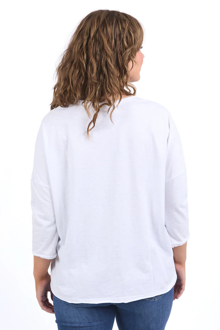 A woman viewed from the back wearing a white three-quarter sleeve top and blue jeans against a plain white background.
