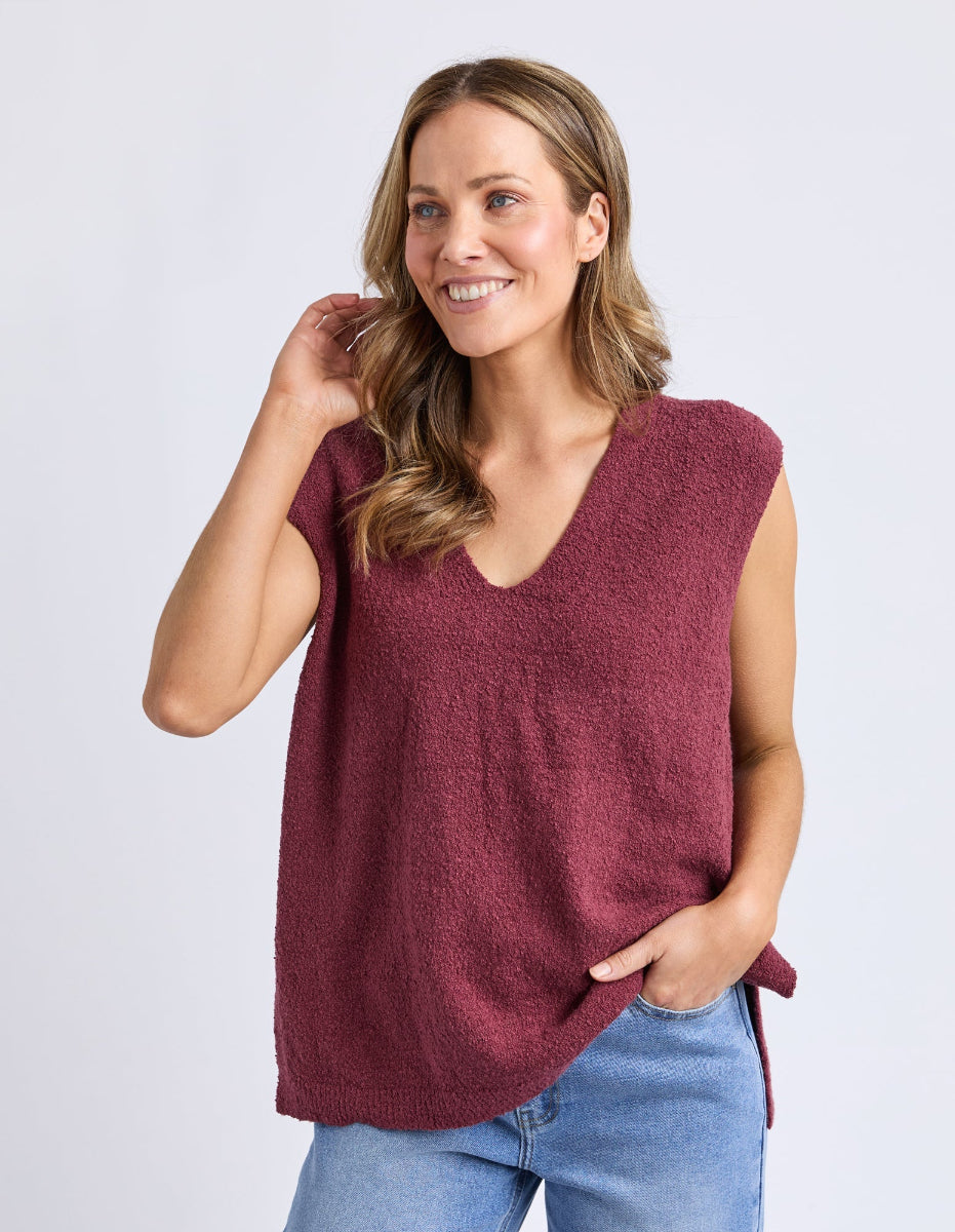 Close view of plum sleeveless knit top styled casually.