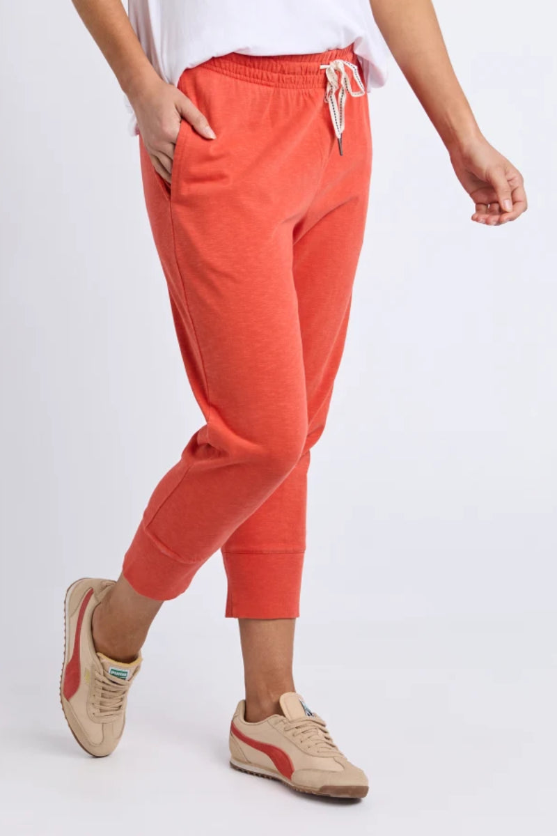 Person wearing bright orange jogger pants with a white background