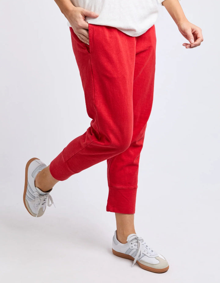 Side view of red cropped jogger pants with white sneakers.