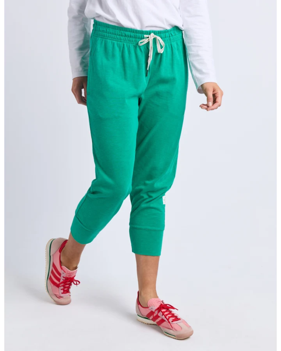 Person wearing green jogger pants and pink sneakers on a white background